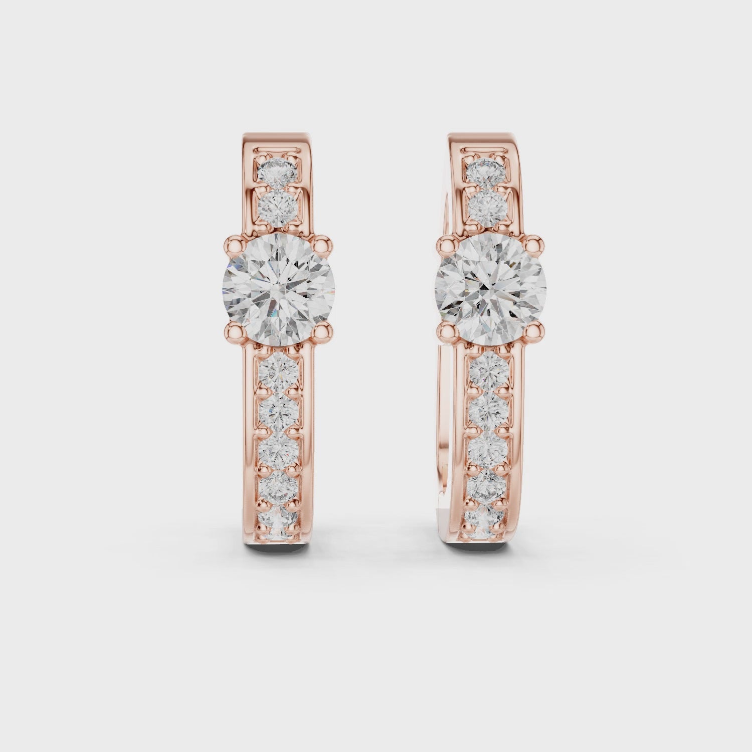 Rose gold diamond hoop earrings with a central round diamond and smaller diamonds along the band.